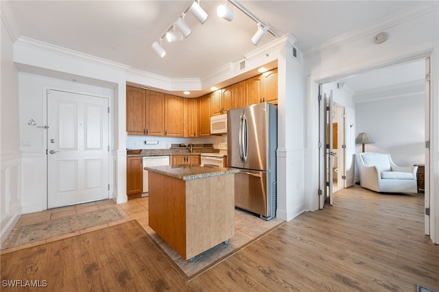 kitchen featuring sink, light wood-type flooring, a center island, crown molding, and white appliances