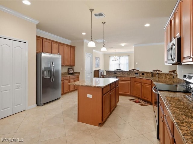 kitchen featuring crown molding, stone counters, appliances with stainless steel finishes, hanging light fixtures, and a kitchen island