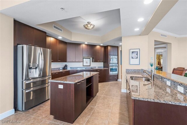 kitchen with dark brown cabinetry, sink, light stone counters, and stainless steel refrigerator with ice dispenser