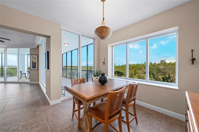 dining room featuring ceiling fan, plenty of natural light, a wall of windows, and light tile patterned floors