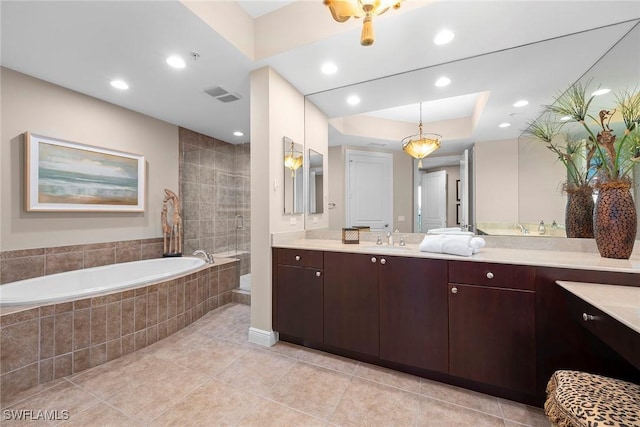 bathroom featuring vanity, a tray ceiling, tile patterned flooring, and tiled bath