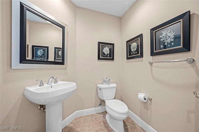 bathroom featuring tile patterned floors, toilet, baseboards, and a sink