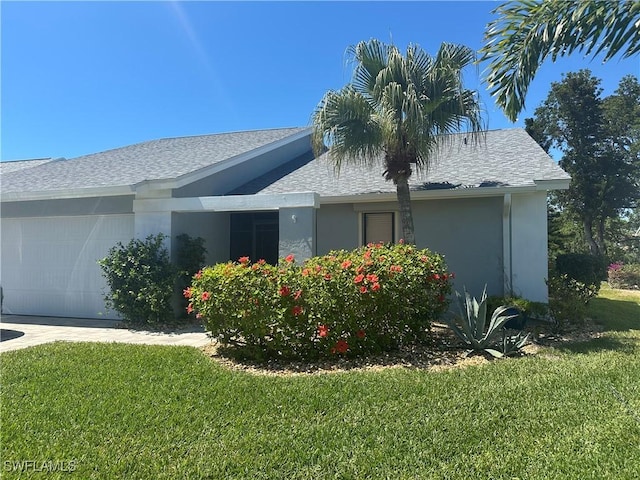 view of property exterior with a garage, a yard, a shingled roof, and stucco siding