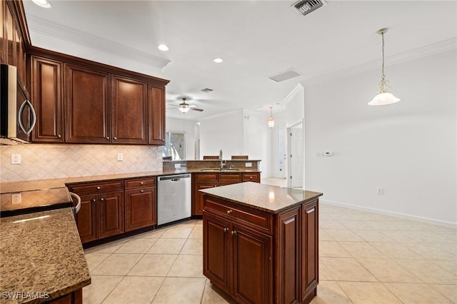 kitchen with pendant lighting, ornamental molding, a center island, stainless steel appliances, and light stone countertops