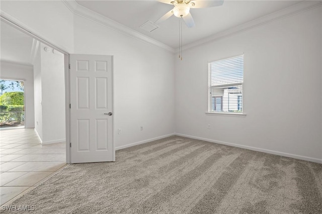 empty room featuring ornamental molding, a ceiling fan, light carpet, light tile patterned flooring, and baseboards