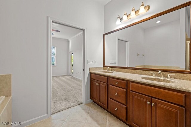 bathroom featuring baseboards, double vanity, a sink, and tile patterned floors