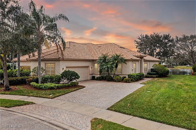 view of front of property with decorative driveway, a yard, a garage, and stucco siding