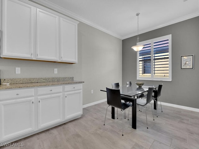 dining room with ornamental molding and light hardwood / wood-style flooring