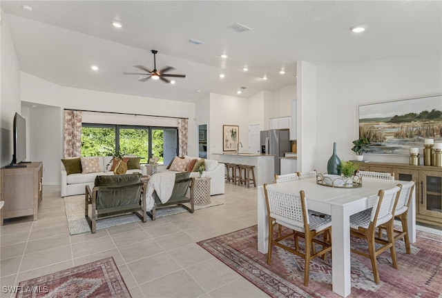 dining area featuring vaulted ceiling, sink, light tile patterned floors, ceiling fan, and a textured ceiling