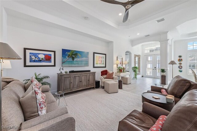 tiled living room featuring french doors, a raised ceiling, and a high ceiling