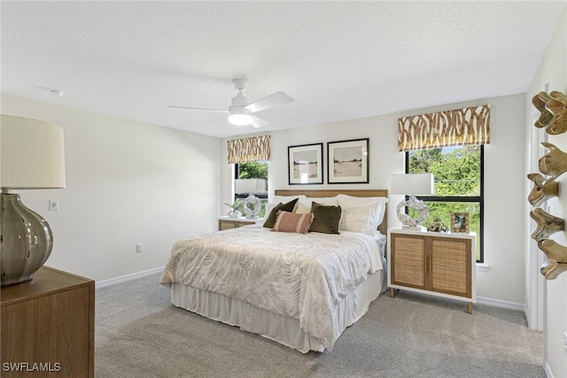 bedroom featuring ceiling fan, light colored carpet, and a textured ceiling