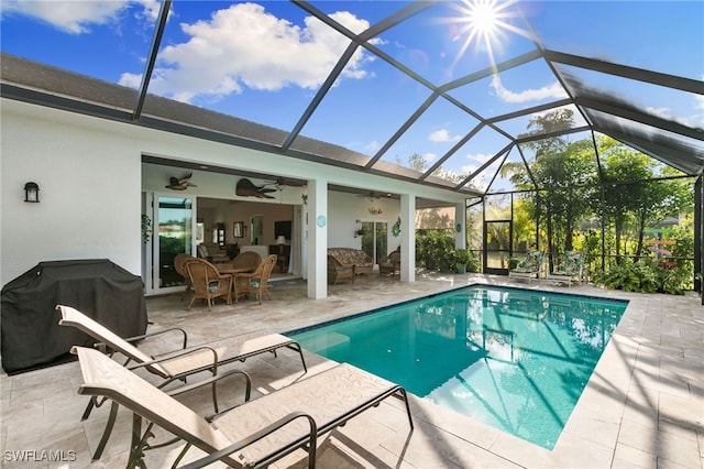 view of swimming pool with ceiling fan, a patio, area for grilling, and glass enclosure