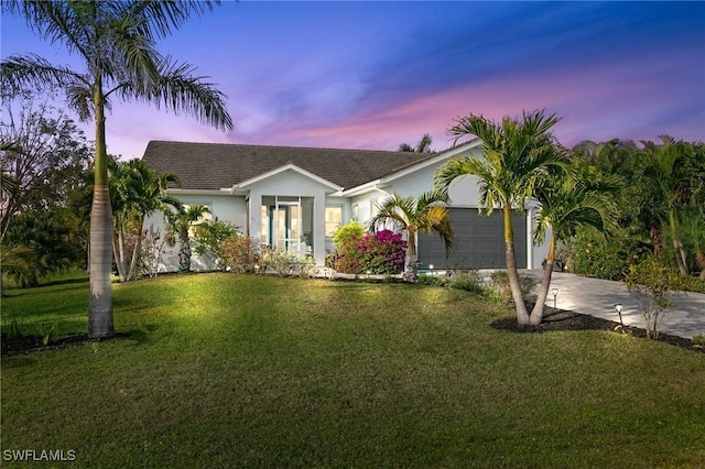 ranch-style house featuring a garage and a lawn