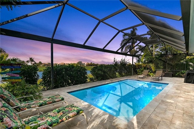 pool at dusk featuring a lanai and a patio