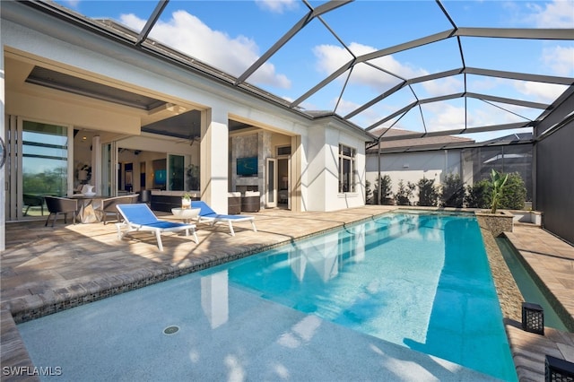 view of pool with an outdoor living space with a fireplace, ceiling fan, a lanai, and a patio