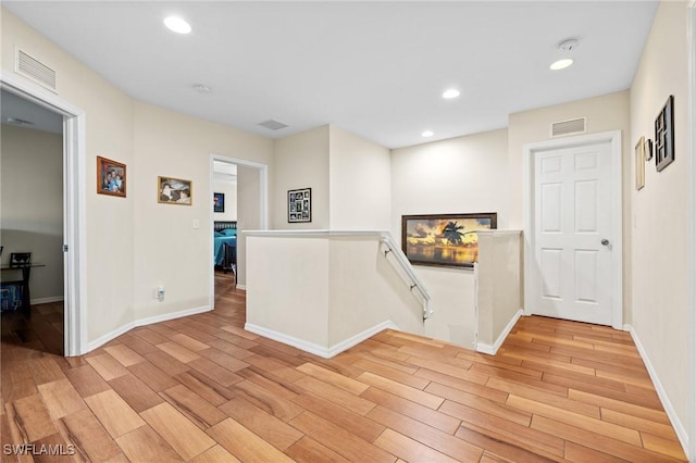 hallway with visible vents, recessed lighting, an upstairs landing, and light wood-style floors