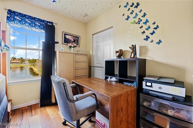 home office featuring a textured ceiling, light wood-style flooring, and baseboards