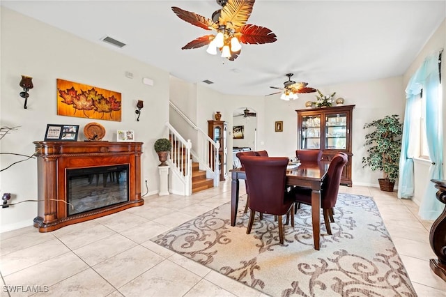 dining area featuring stairs, plenty of natural light, a glass covered fireplace, and visible vents