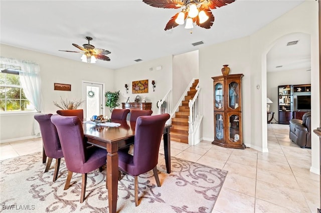 dining space with light tile patterned floors, stairway, visible vents, and arched walkways