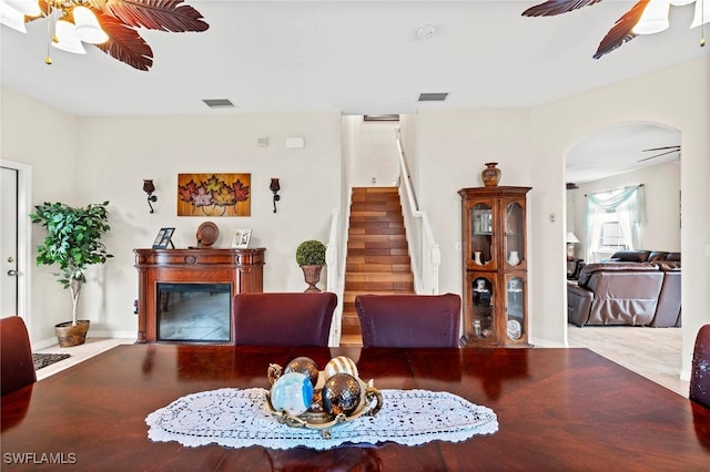 living area featuring a glass covered fireplace, visible vents, and ceiling fan