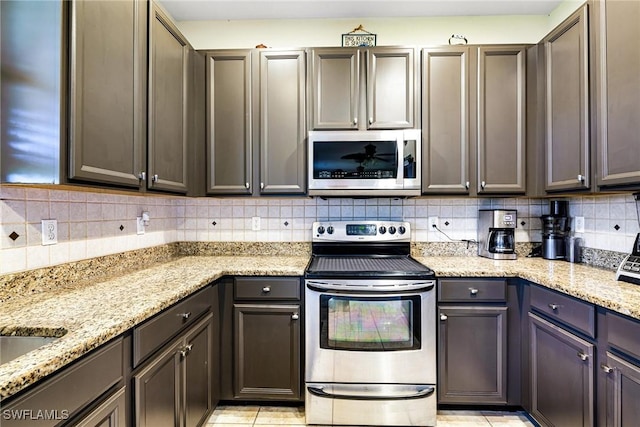 kitchen featuring stainless steel appliances, light stone counters, and tasteful backsplash