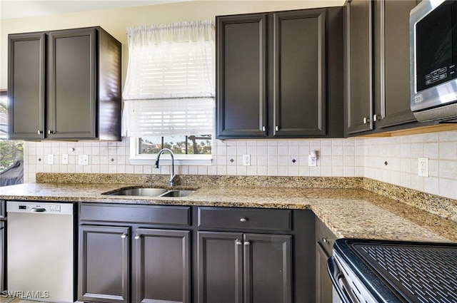 kitchen with decorative backsplash, appliances with stainless steel finishes, light stone counters, and a sink