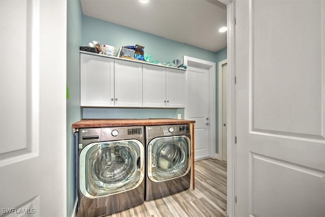 washroom with separate washer and dryer, light hardwood / wood-style floors, and cabinets