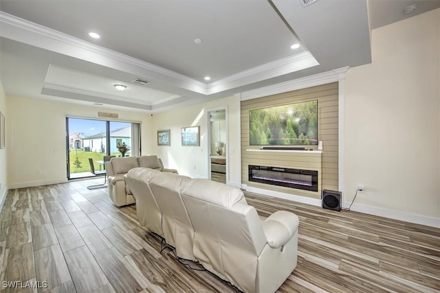 living room featuring crown molding, a tray ceiling, and light hardwood / wood-style flooring