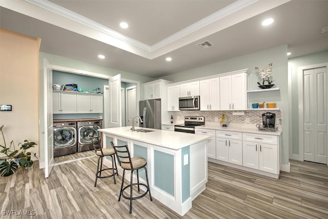 kitchen with white cabinetry, sink, a kitchen island with sink, independent washer and dryer, and stainless steel appliances