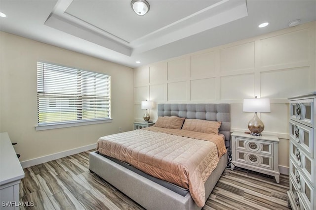 bedroom featuring a raised ceiling and light wood-type flooring