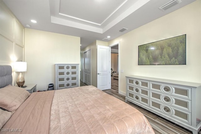 bedroom featuring a closet, hardwood / wood-style flooring, and a raised ceiling