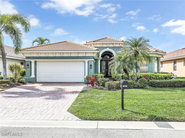 mediterranean / spanish-style house with a garage, a front yard, and french doors