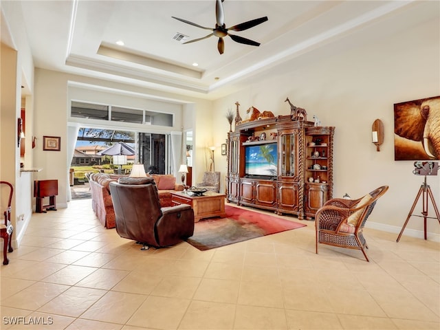 tiled living room featuring ceiling fan and a tray ceiling