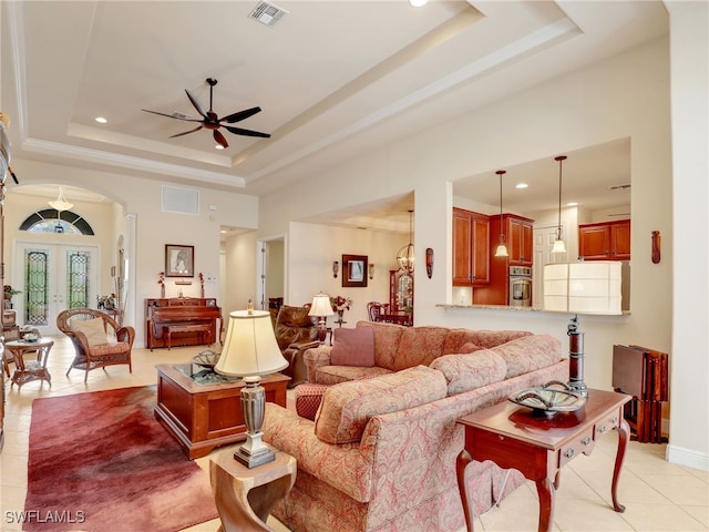 tiled living room featuring a towering ceiling, a raised ceiling, ceiling fan, and french doors