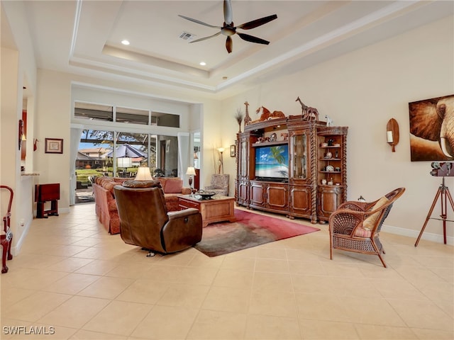 living room with light tile patterned floors, a tray ceiling, ceiling fan, and a towering ceiling