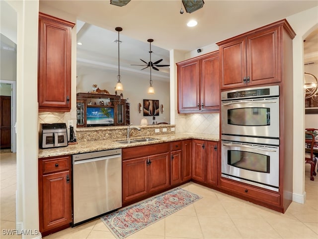 kitchen with sink, light stone counters, appliances with stainless steel finishes, kitchen peninsula, and pendant lighting