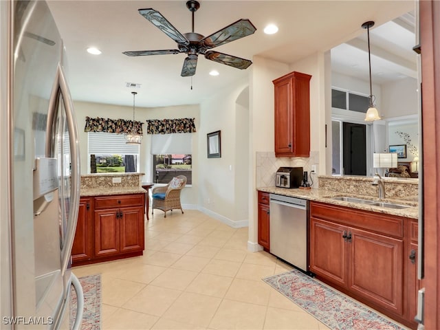 kitchen with appliances with stainless steel finishes, sink, decorative backsplash, hanging light fixtures, and light stone countertops