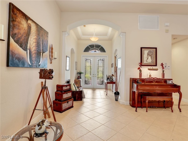 tiled entryway with crown molding, a tray ceiling, and french doors