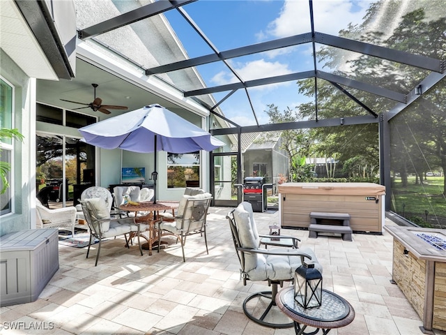 view of patio / terrace featuring ceiling fan, a hot tub, and a lanai