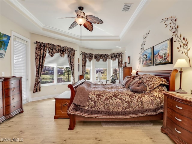 bedroom featuring crown molding, a tray ceiling, ceiling fan, and light wood-type flooring