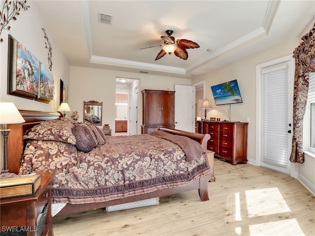 bedroom featuring a raised ceiling, ceiling fan, connected bathroom, and light hardwood / wood-style floors