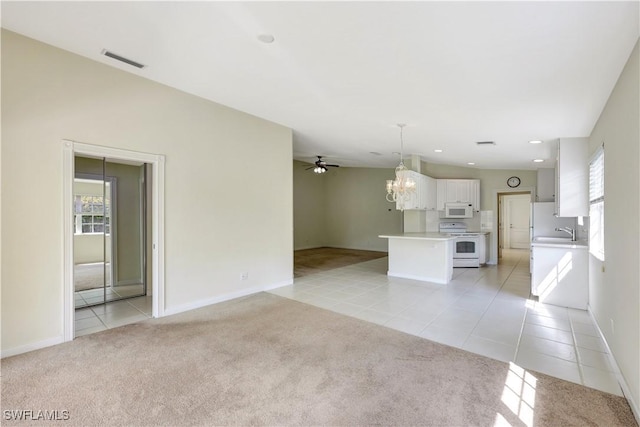 unfurnished living room with a wealth of natural light, ceiling fan with notable chandelier, sink, and light carpet