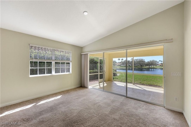 carpeted spare room with lofted ceiling, a healthy amount of sunlight, and a water view