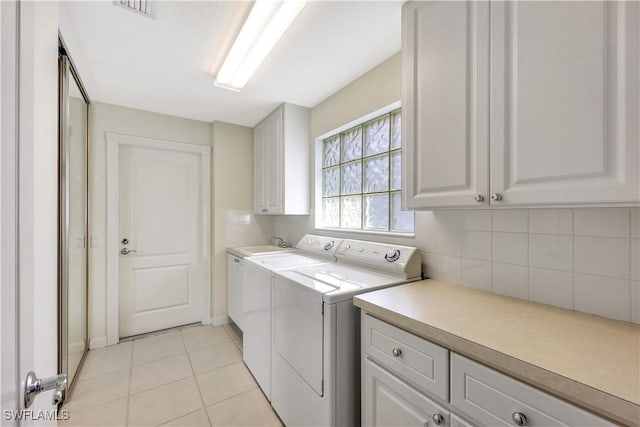 clothes washing area featuring cabinets, sink, washer and dryer, and light tile patterned floors