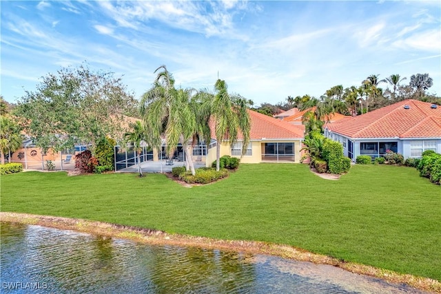 back of house featuring a water view and a lawn