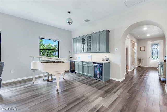 9368 Night Heron Ln, Naples, FL 34120 - indoor bar with wine cooler, arched walkways, dark wood-type flooring, baseboards, and decorative light fixtures
