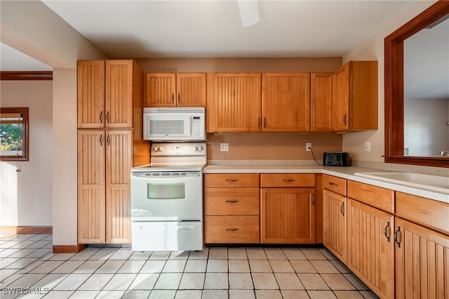 kitchen featuring sink, light tile patterned floors, and white appliances