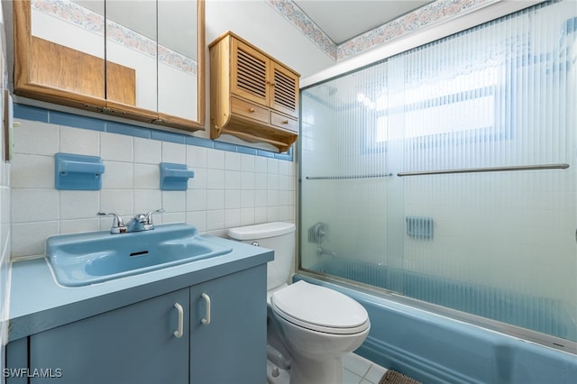 full bathroom featuring combined bath / shower with glass door, tile walls, decorative backsplash, vanity, and toilet