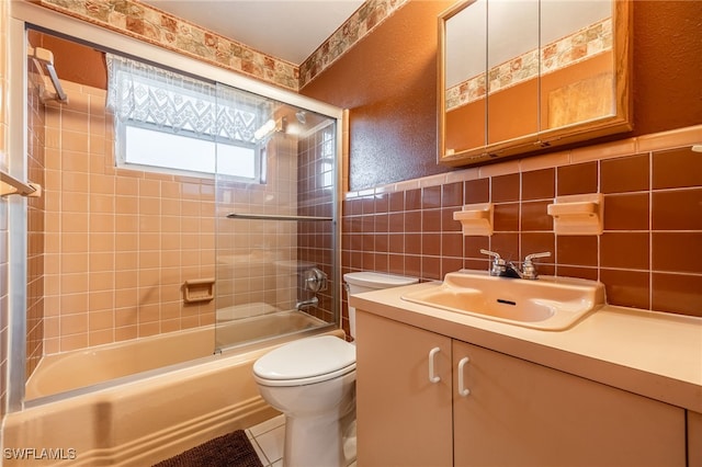 full bathroom with tile walls, tile patterned flooring, tiled shower / bath combo, vanity, and toilet