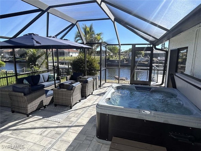 view of patio / terrace with a hot tub, glass enclosure, and a water view